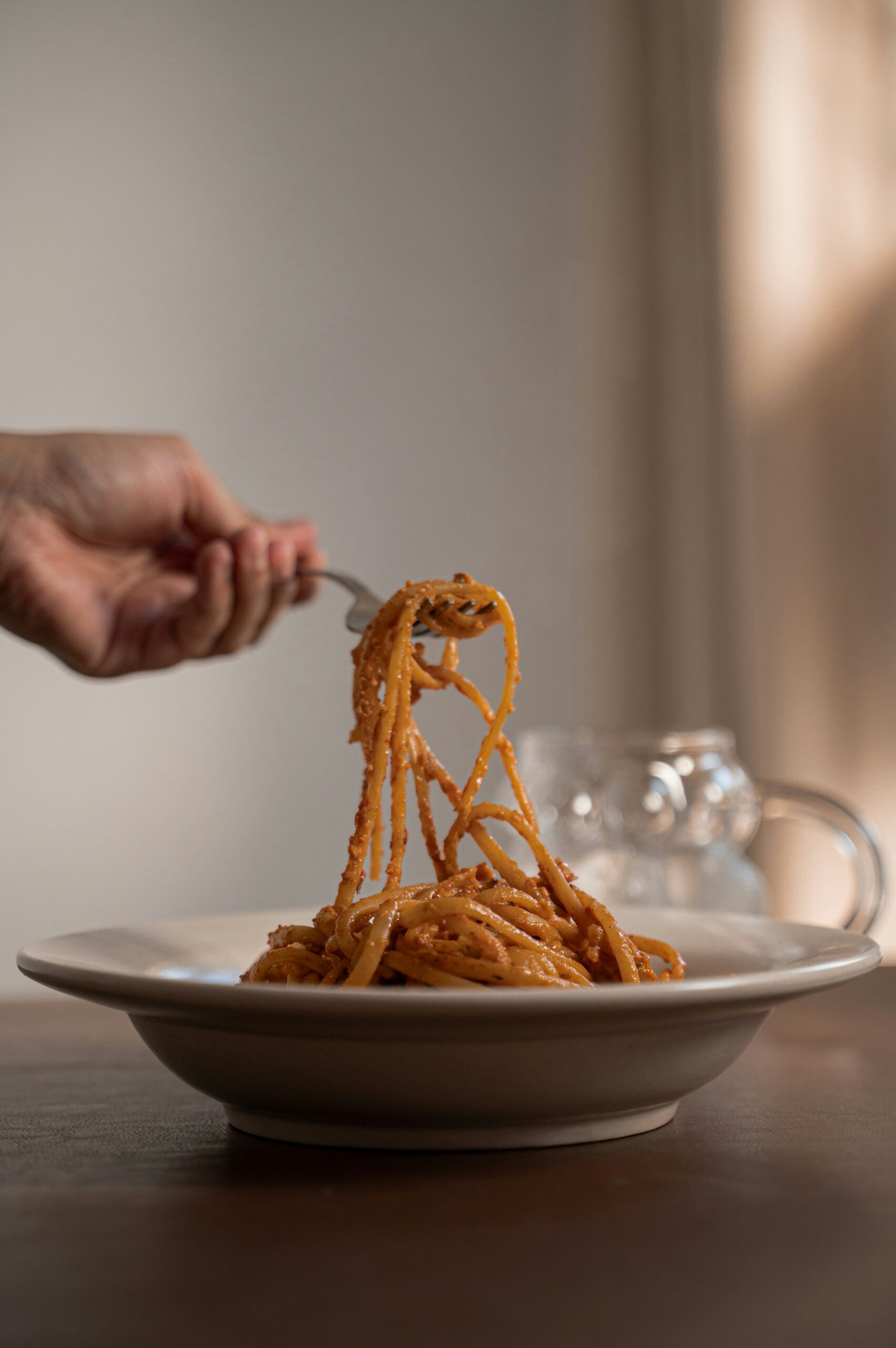 A plate of spaghetti being eaten with a fork